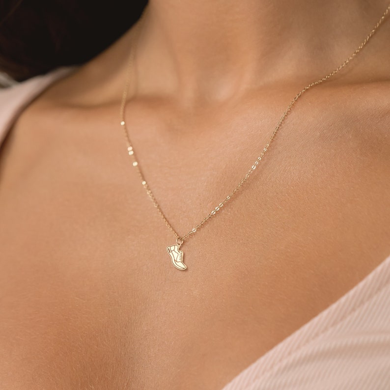 May include: A gold chain necklace with a small shoe charm pendant.