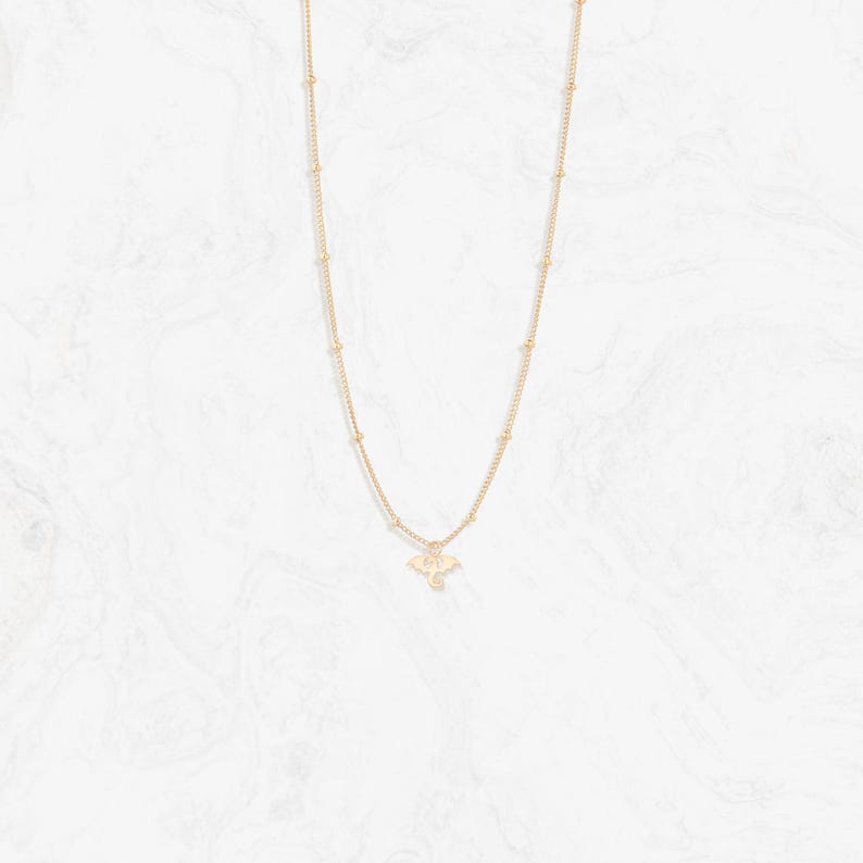 May include: A gold necklace with a delicate chain and a small bat pendant.