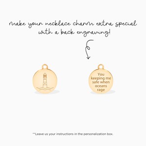 May include: Gold-toned necklace charm with a lighthouse design on the front and the inscription "You keeping me safe when oceans rage" on the back.