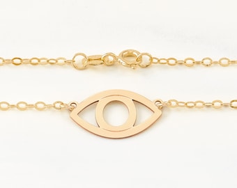 Könnte beinhalten: Eine goldene Kettenkette mit einem zarten Augenanhänger. Das Auge ist offen und hat eine runde Pupille. Die Kette ist eine einfache, verlinkte Kette.