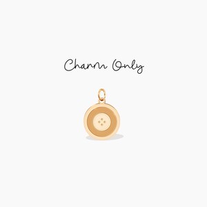 May include: Gold charm with a round, button-like design. The button has a white center with four small gold dots.