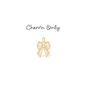 Könnte beinhalten: Ein goldfarbener Schleifenanhänger mit einer Schlaufe zum Aufhängen. Der Anhänger ist auf weißem Hintergrund zentriert, darüber steht in Schreibschrift "Charm Only".