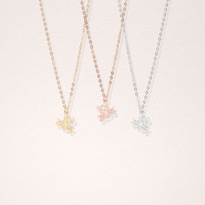 May include: Three delicate necklaces with geometric frog pendants. The necklaces are available in gold, rose gold, and silver.