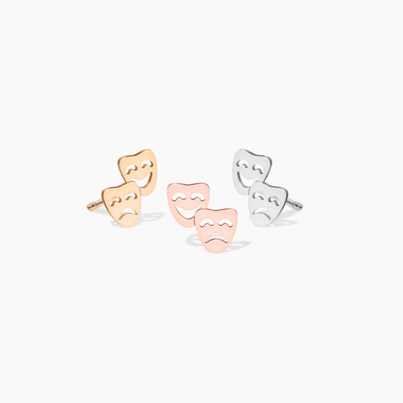 May include: A set of three pairs of earrings featuring a classic theater mask design. The earrings are available in gold, rose gold, and silver.