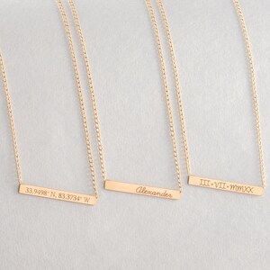 May include: Three gold necklaces with personalized bar pendants. The pendants are engraved with "33.9498&deg; N, 83.3734&deg; W", "Alexander", and "III&bull;VII&bull;MMXX".