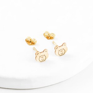 May include: A pair of gold-toned bear-shaped stud earrings. The earrings are small and delicate, and they would make a great gift for a child.