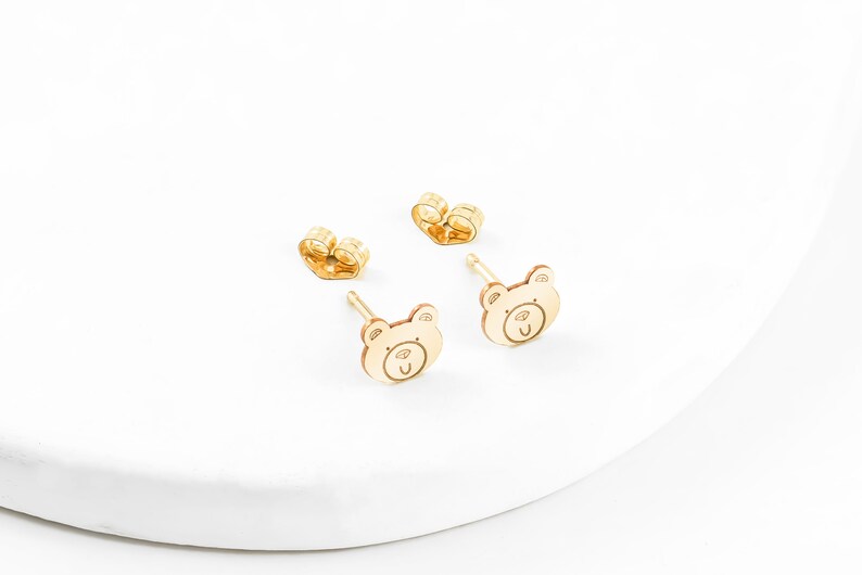 May include: A pair of gold-toned bear-shaped stud earrings. The earrings are small and delicate, and they would make a great gift for a child.