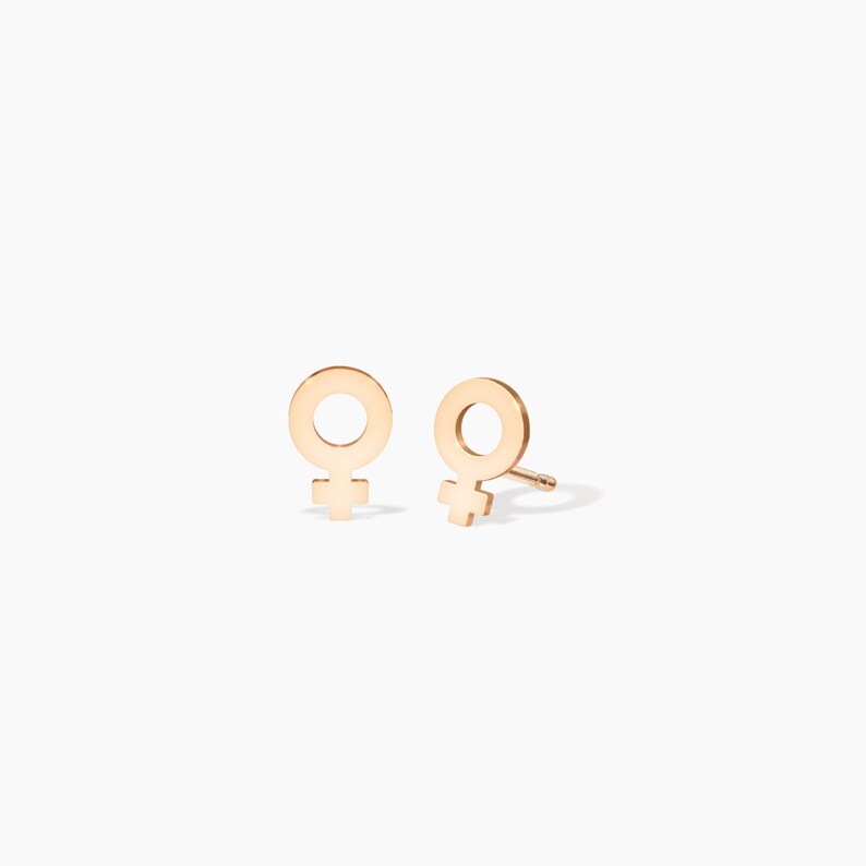 May include: A pair of gold-toned stud earrings featuring a female symbol design.