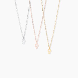 May include: Three delicate necklaces with a feminine symbol pendant. The necklaces are silver, rose gold, and gold.
