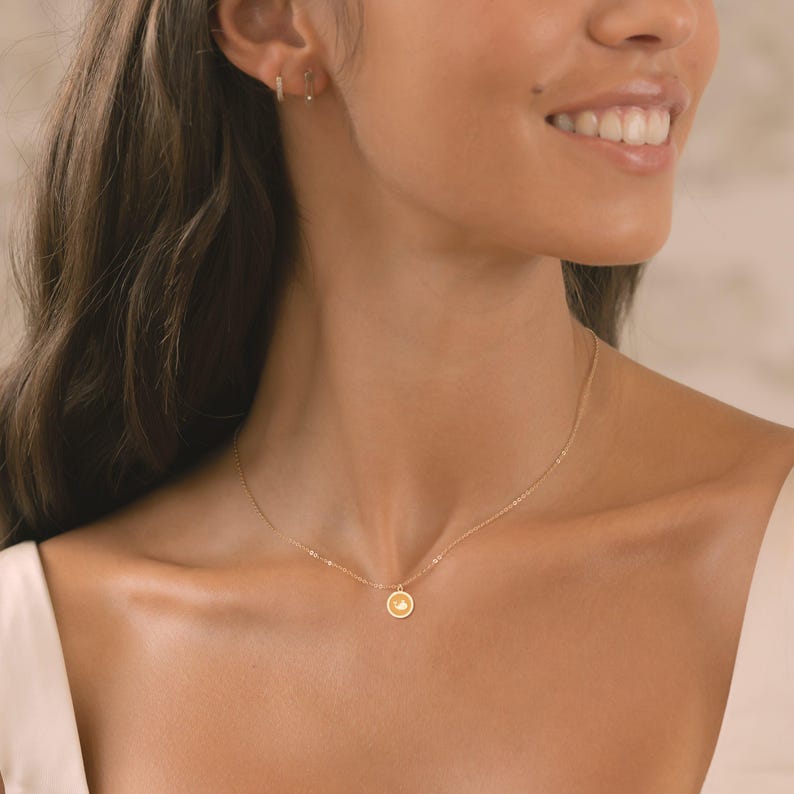 Delicate gold charm pendant necklace featuring a simple circular design, perfect for everyday wear or special occasions. Ideal for minimalists seeking elegance in their jewelry collection.