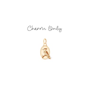 May include: Gold-colored charm with an oval pendant featuring a detailed illustration of a bird perched on a branch. The charm has a loop at the top for attachment. The text "Charm Only" is written above the charm.