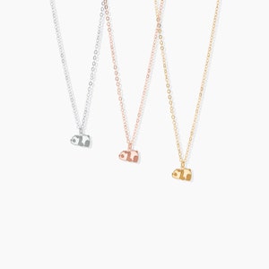 May include: Three delicate necklaces with panda bear pendants. The necklaces are silver, rose gold, and gold. Each panda pendant is a different color, with black and white, brown and white, and brown and tan accents.