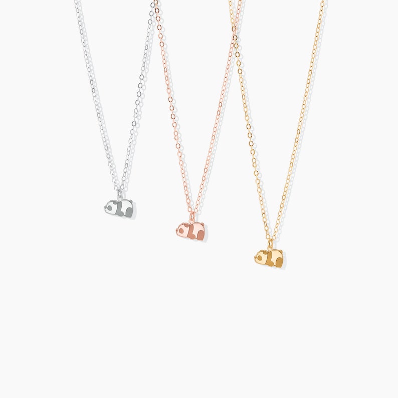 May include: Three delicate necklaces with panda bear pendants. The necklaces are silver, rose gold, and gold. Each panda pendant is a different color, with black and white, brown and white, and brown and tan accents.