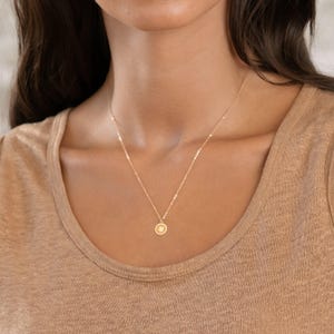 Delicate gold charm pendant necklace featuring a circular charm with a leaf design. Ideal for nature lovers or casual wear, this minimalist accessory adds a touch of elegance to any outfit.