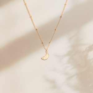 Op de afbeelding: Een gouden ketting met een klein bananenbedeltje.