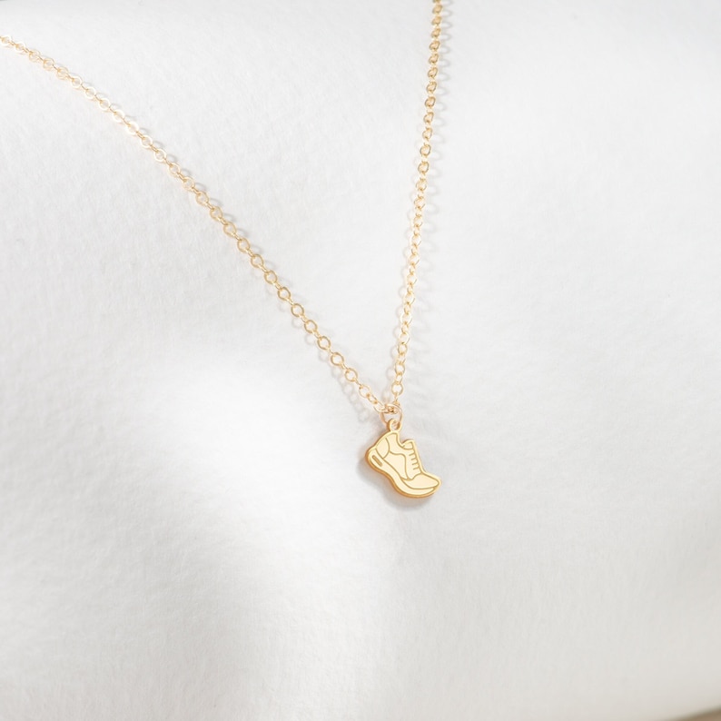May include: A gold chain necklace with a small gold shoe pendant.