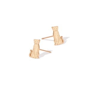 May include: A pair of rose gold stud earrings shaped like sitting cheetahs. Each earring features a detailed engraved outline of a cheetah with visible spots and a post back for secure attachment. The metal has a warm, metallic pinkish hue.