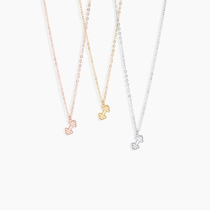May include: Three delicate necklaces with dumbbell pendants. The necklaces are available in gold, rose gold, and silver.