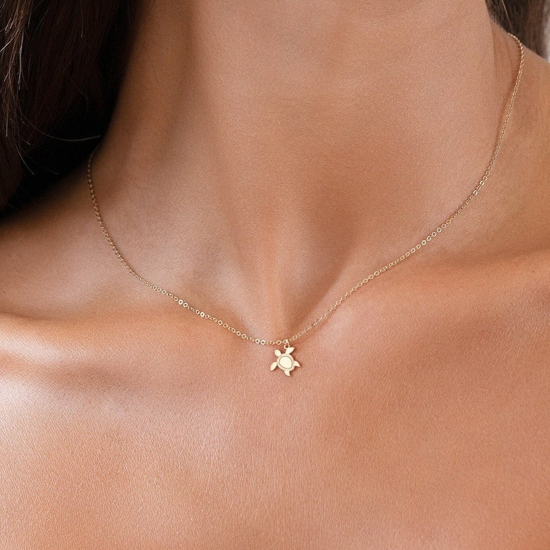 May include: A gold chain necklace with a small turtle pendant.