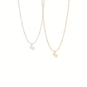 May include: Two delicate necklaces with a dainty chain and a small charm of two theater masks, one in silver and one in gold.
