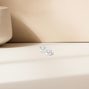 May include: A pair of silver skull stud earrings with a floral design. The earrings are small and delicate.