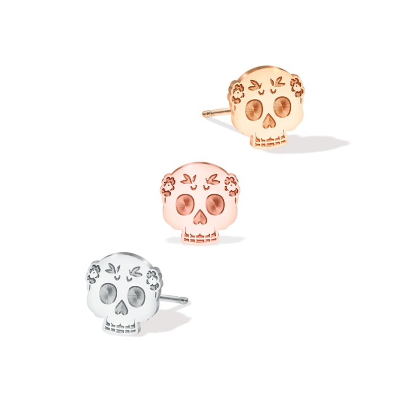 May include: Three silver, rose gold, and gold sugar skull earrings. Each earring features a detailed sugar skull design with floral accents.