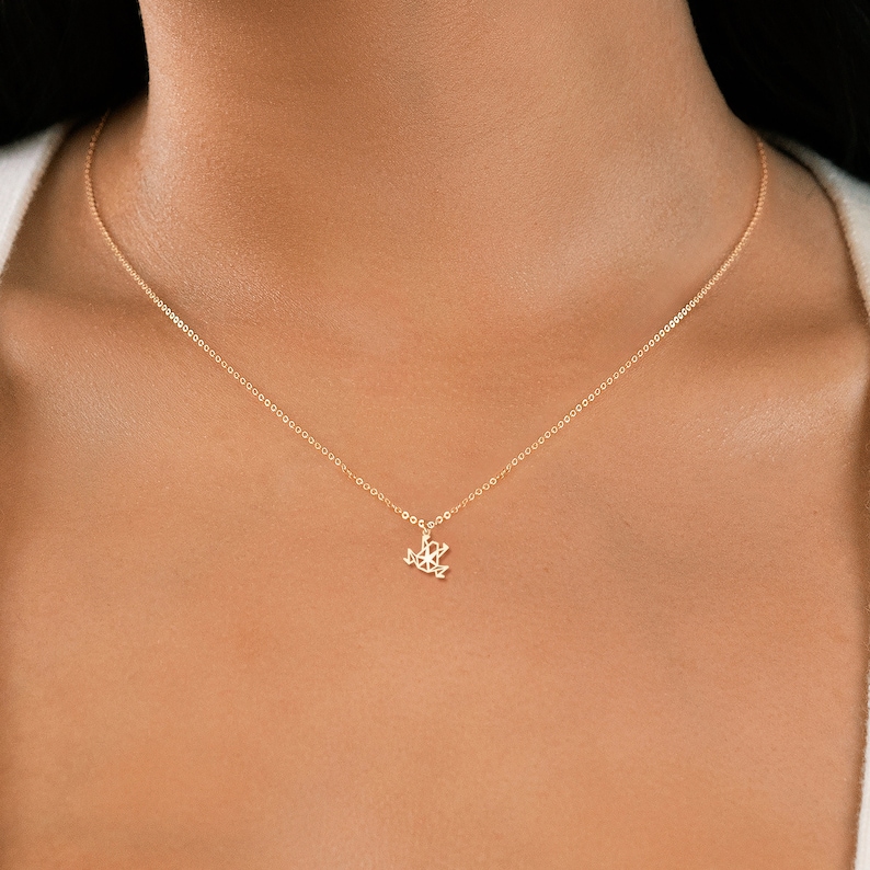 May include: A gold chain necklace with a delicate frog pendant.