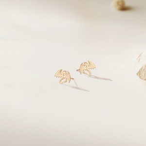 May include: A pair of gold dragon stud earrings. The earrings are small and delicate, with a detailed dragon design.