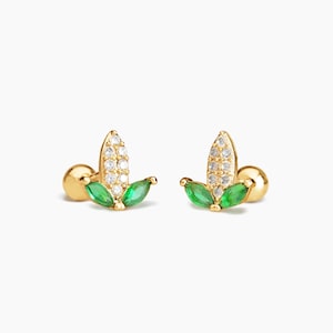 May include: A pair of gold-toned earrings with a leaf design. Each earring features a small, round ball at the bottom, followed by two green marquise-shaped stones, and a larger, pointed leaf-shaped piece with clear round stones.
