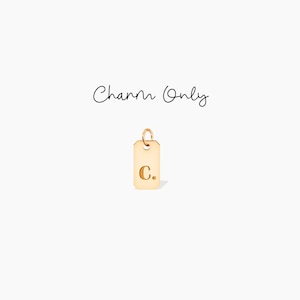 May include: A gold-colored rectangular charm with rounded corners and a small loop at the top. The charm has the letter "C" engraved on it. The words "Charm Only" are written in cursive above the charm.