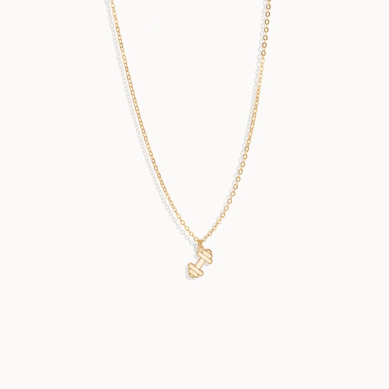 May include: A gold chain necklace with a small gold dumbbell pendant.
