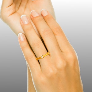 K&ouml;nnte beinhalten: Ein Goldring mit drei kleinen quadratischen Diamanten.