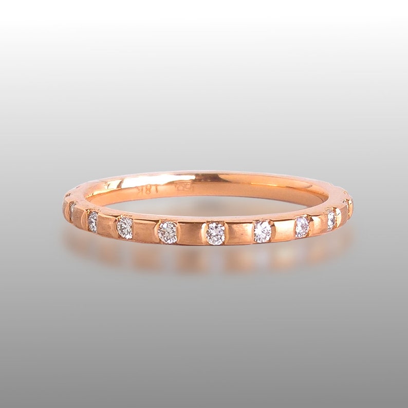Pu&ograve; includere: Un anello a fascia in oro rosa con una fila di piccoli diamanti incastonati nella fascia.