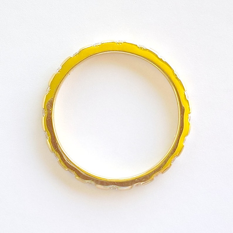 Pu&ograve; includere: Un anello d'oro con una fascia in smalto giallo e un design decorativo.