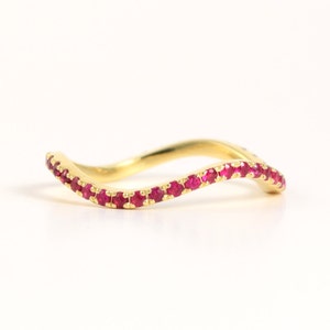 Könnte beinhalten: Ein zarter Goldring mit wellenförmigem Design, verziert mit einer Reihe kleiner roter Rubine.