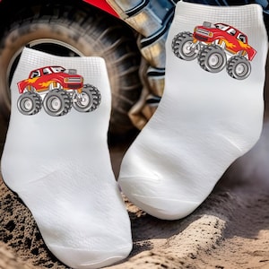 May include: A pair of white ankle socks with a red monster truck graphic on each sock. The truck has flames on the side and large black tires.