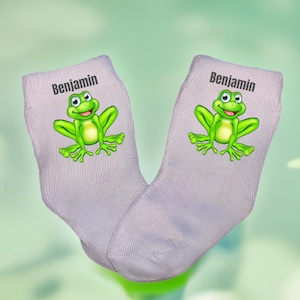 May include: A pair of grey socks with a green frog and the name "Benjamin" printed on them.