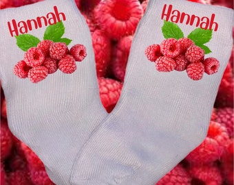 May include: A pair of white socks with a red raspberry design and the name "Hannah" printed on each sock.