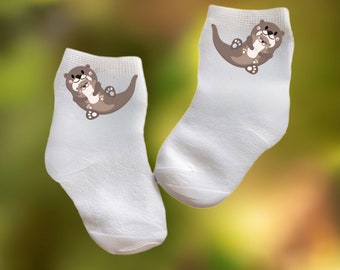 May include: A pair of white ankle socks with a brown cartoon otter and baby otter design.
