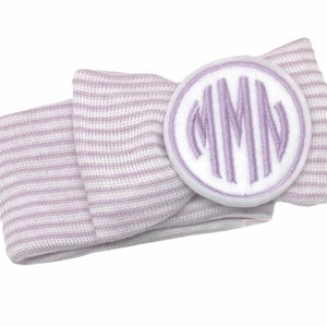 May include: A purple and white striped headband with a white circle monogrammed with the letters "MMN" in purple.