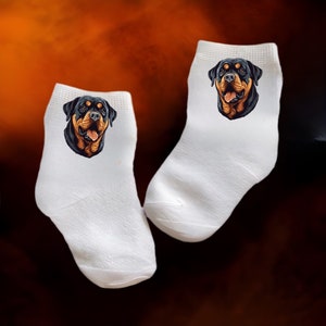 May include: A pair of white ankle socks with a Rottweiler dog face printed on each sock.