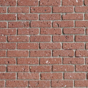 May include: A close-up of a red brick wall with white mortar. The bricks have a rough texture and are arranged in a traditional brick pattern.