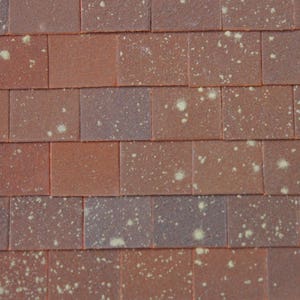 May include: A close-up of a brick wall with a red-brown colour and white speckles throughout. The bricks are arranged in a staggered pattern.