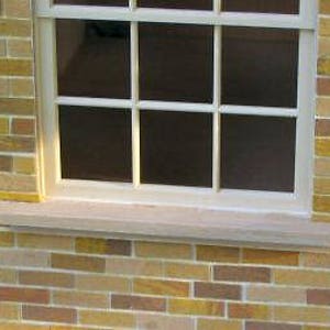 May include: A brick wall with a window and a stone window sill. The window has six panes of glass.