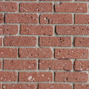 May include: A close-up of a red brick wall with white mortar. The bricks have a rough texture and are arranged in a traditional brick pattern.