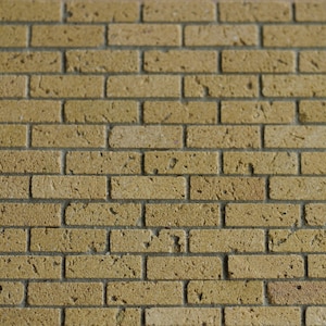 May include: A close-up of a brick wall with a light brown color. The bricks are arranged in a staggered pattern, creating a traditional brick wall look.