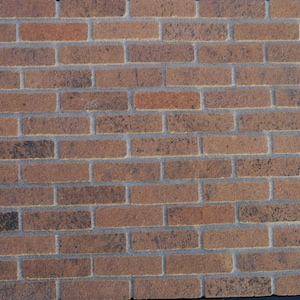 May include: A brick wall with a brown and gray color scheme. The bricks are arranged in a traditional brick pattern.