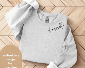 May include: A gray sweatshirt with the word "Hornets" embroidered on the front in black cursive script. This is a machine embroidery design.