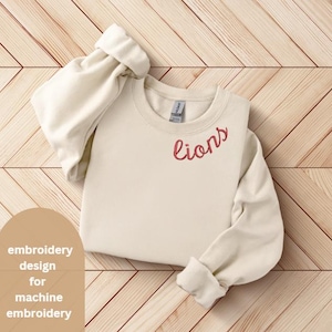 May include: Cream-colored sweatshirt with the word "lions" embroidered in red script. The long sleeves are cuffed, and the garment is displayed on a light wood surface. The design is for machine embroidery.