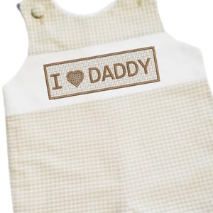May include: A white and brown gingham baby onesie with a brown embroidered rectangle that says "I love Daddy" with a heart in place of the "o".